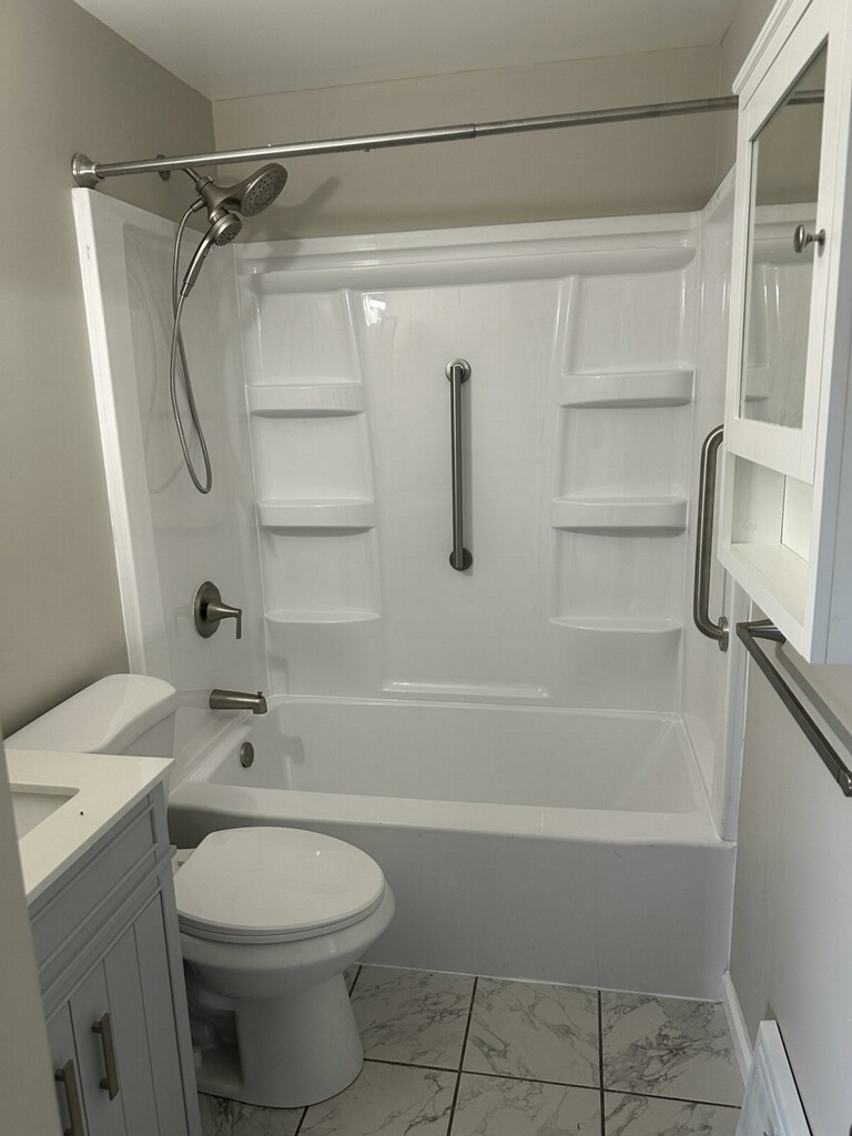 Finished bathroom with new tub, tile surround, and vanity