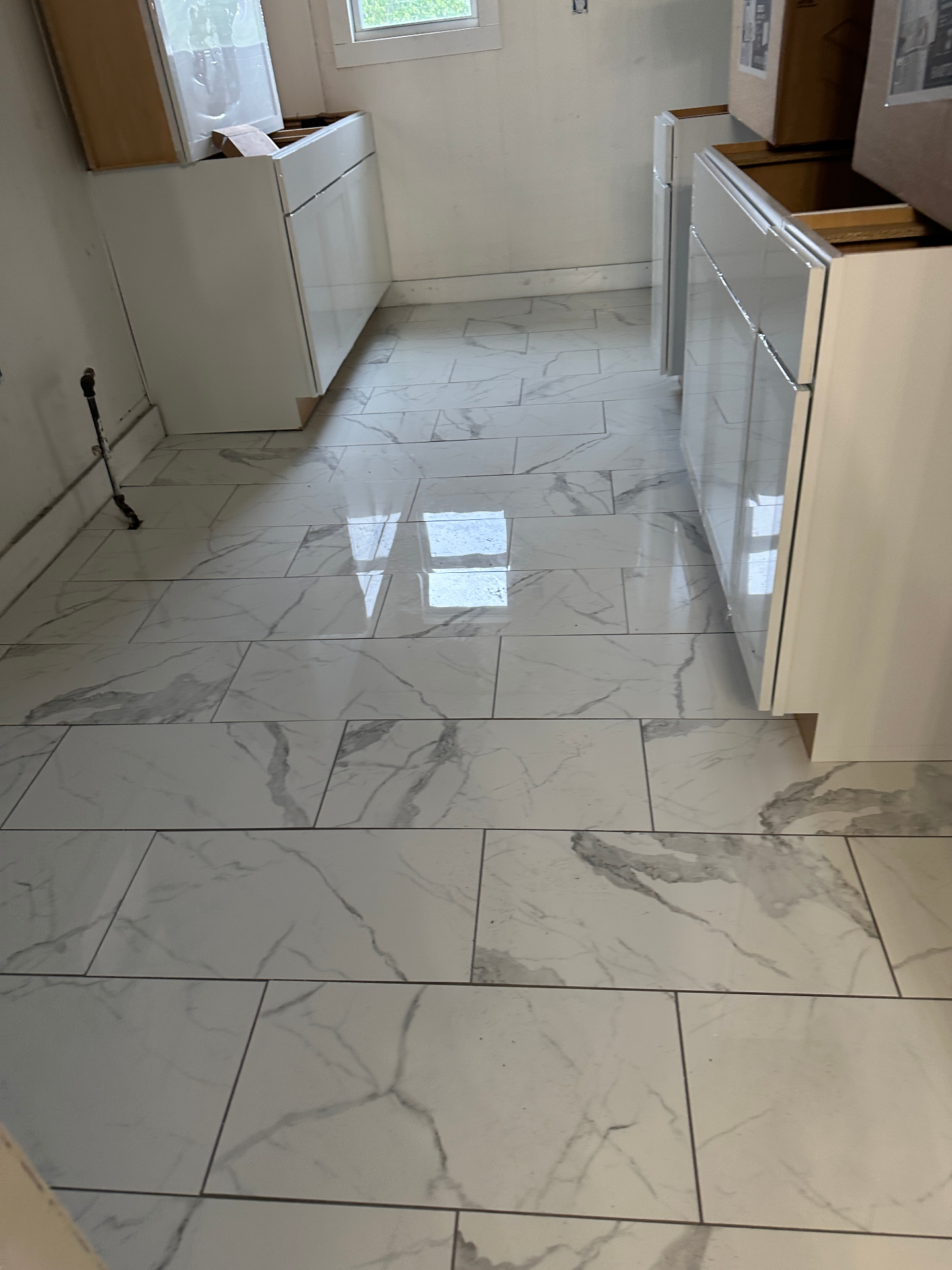 Newly installed white marble-look porcelain tile flooring in kitchen